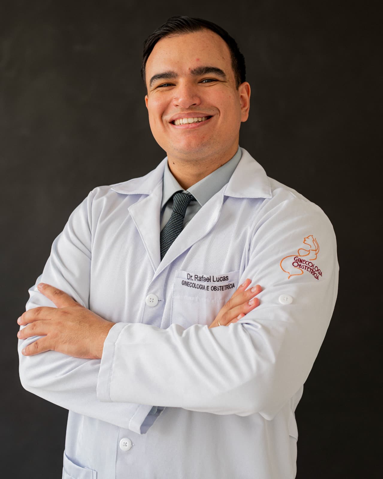 Dr. Rafael com jaleco branco, sorrindo e de braços cruzados