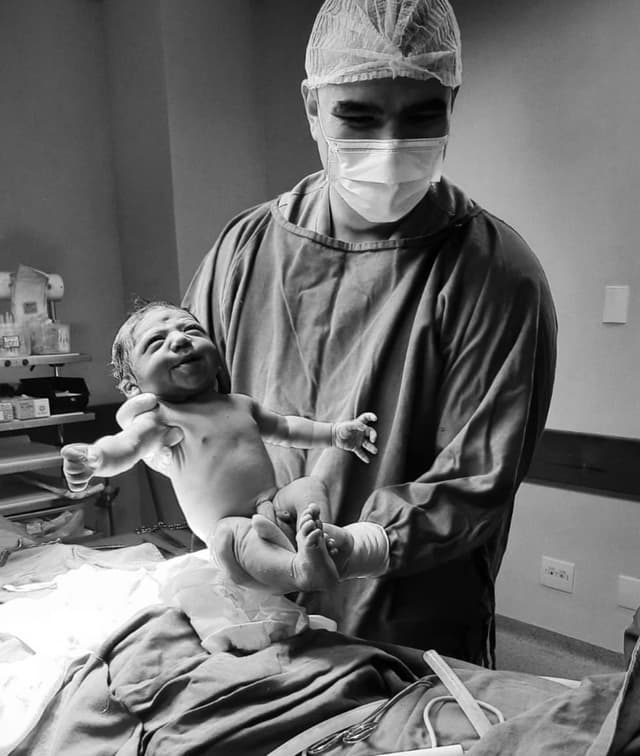 Dr. Rafael Schultz com um bebê no colo após realizar o parto do mesmo